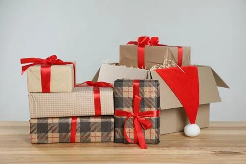 Parcel with gift boxes and Santa hat on wooden table against light background 스톡 사진