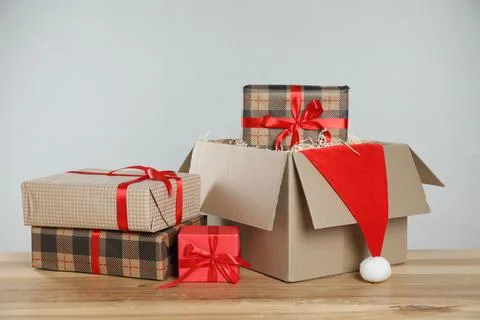 Parcel with gift boxes and Santa hat on wooden table against light background 스톡 사진