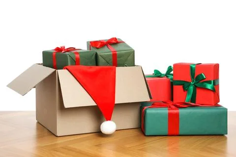 Parcel with gift boxes and Santa hat on wooden table against white background 스톡 사진