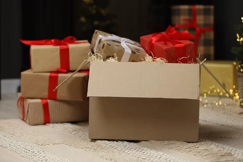 Parcel with gift boxes on floor in room decorated for Christmas. Bokeh effect Stock Photos