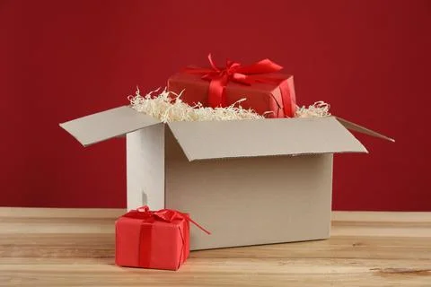 Parcel with gift boxes on wooden table against red background 스톡 사진