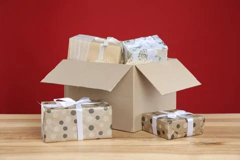 Parcel with gift boxes on wooden table against red background Foto stock