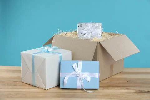 Parcel with gift boxes on wooden table against light blue background Foto stock