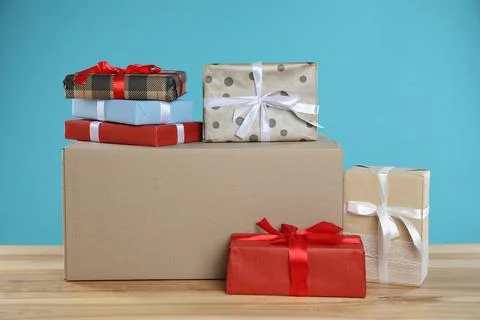 Parcel with gift boxes on wooden table against light blue background Foto stock