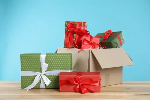 Parcel with gift boxes on wooden table against light blue background Foto stock