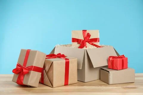 Parcel with gift boxes on wooden table against light blue background 스톡 사진