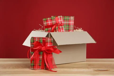Parcel with gift boxes on wooden table against red background 스톡 사진