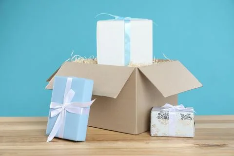 Parcel with gift boxes on wooden table against light blue background 스톡 사진