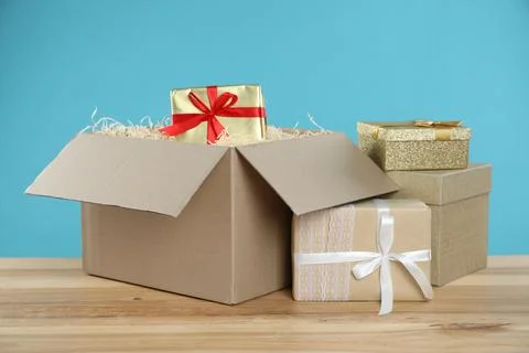 Parcel with gift boxes on wooden table against light blue background Foto stock
