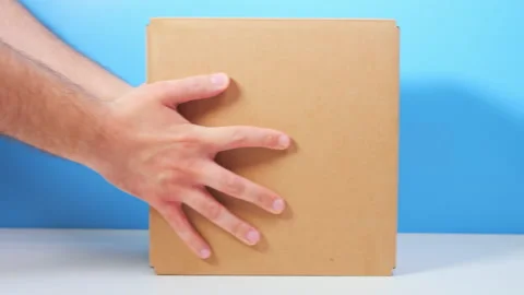 A parcel with humanitarian aid. A man puts a cardboard box with provisions on 스톡 동영상 172346853