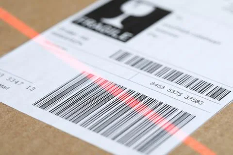 Parcel with label, closeup. Red laser light on barcode for scanning Photos