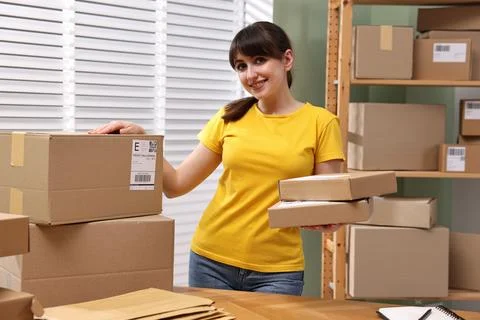 Parcel packing. Post office worker with parcels at wooden table indoors Stock Photos