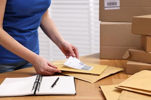 Parcel packing. Post office worker sticking barcode on bag at wooden table .. Stock Photos
