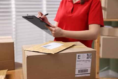 Parcel packing. Post office worker with clipboard indoors, closeup Stockfoto's