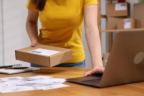 Parcel packing. Post office worker with box using laptop at wooden table in.. Foto stock