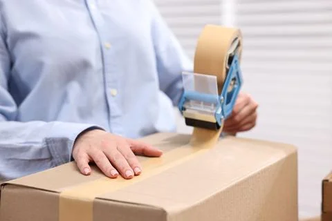 Parcel packing. Post office worker taping box indoors, closeup Stock Photos