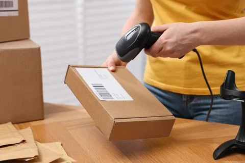 Parcel packing. Post office worker with scanner reading barcode at wooden t.. Photos