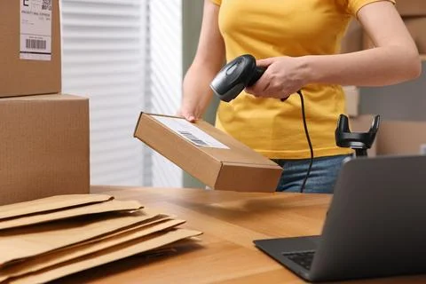 Parcel packing. Post office worker with scanner reading barcode at wooden t.. Stock Photos
