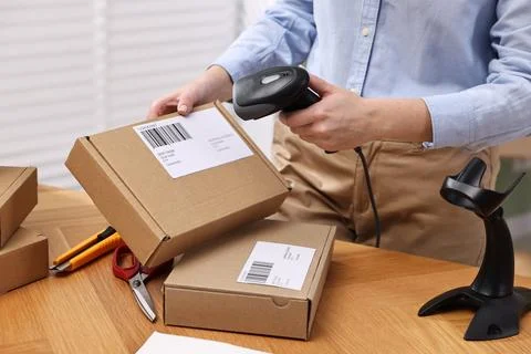 Parcel packing. Post office worker with scanner reading barcode at wooden t.. Stock Photos