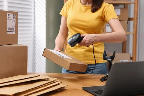 Parcel packing. Post office worker with scanner reading barcode at wooden t.. Photos