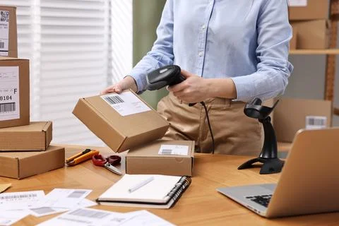Parcel packing. Post office worker with scanner reading barcode at wooden t.. Photos