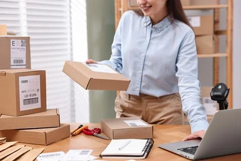 Parcel packing. Post office worker using laptop at wooden table indoors, cl.. Photos