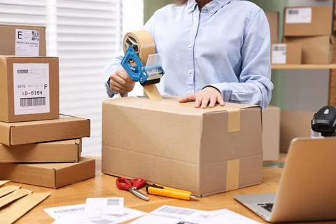 Parcel packing. Post office worker taping box at wooden table indoors, closeu Foto stock