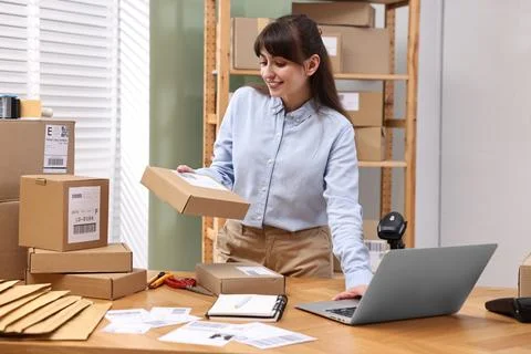 Parcel packing. Post office worker using laptop at wooden table indoors Foto stock