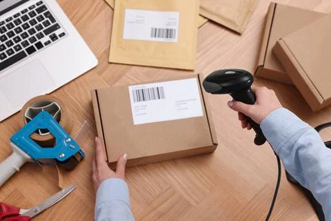 Parcel packing. Post office worker with scanner reading barcode at wooden t.. Foto stock