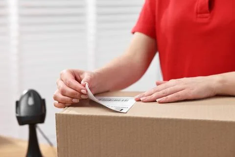Parcel packing. Post office worker sticking barcode on box indoors, closeup Stock Photos