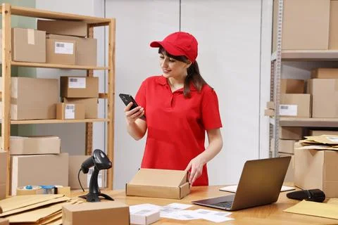 Parcel packing. Post office worker with smartphone and box indoors Photos