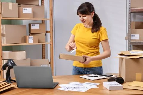 Parcel packing. Post office worker sticking barcode on box at wooden table .. Stock Photos