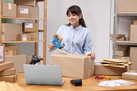 Parcel packing. Post office worker taping box at wooden table indoors Foto stock