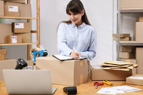 Parcel packing. Post office worker with clipboard writing notes at wooden t.. Stock Photos