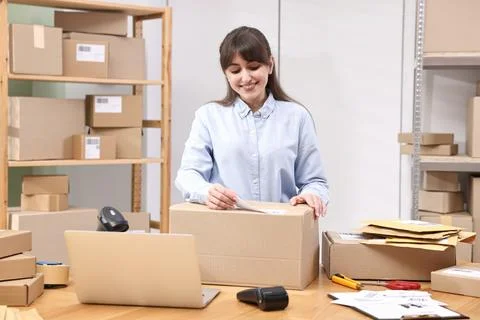 Parcel packing. Post office worker sticking barcode on box at wooden table .. Foto stock