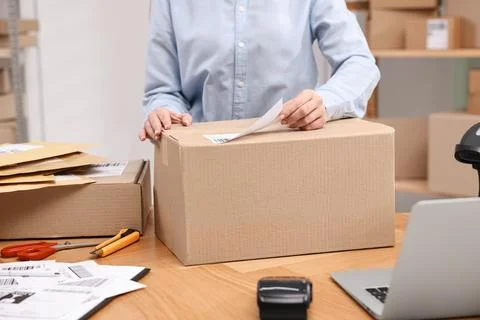 Parcel packing. Post office worker sticking barcode on box at wooden table .. Stock Photos