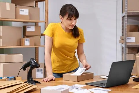 Parcel packing. Post office worker sticking barcode on box at wooden table .. Stock Photos