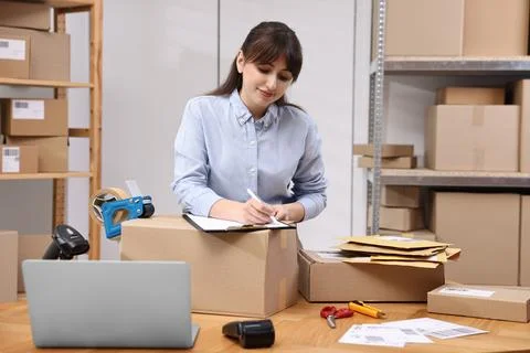 Parcel packing. Post office worker with clipboard writing notes at wooden t.. Stock Photos