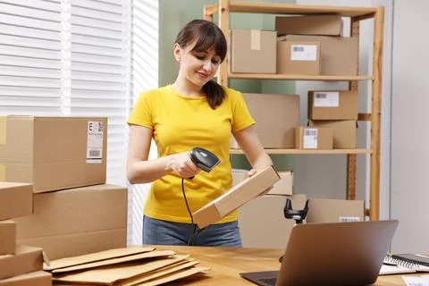 Parcel packing. Post office worker with scanner reading barcode at wooden t.. Foto stock