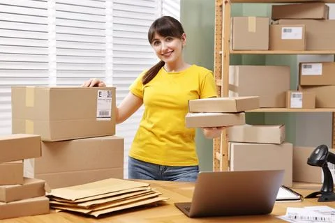 Parcel packing. Post office worker with parcels at wooden table indoors Stock Photos