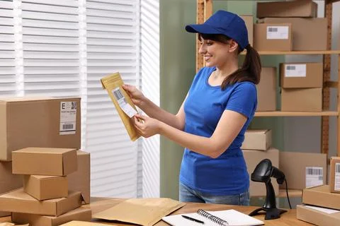 Parcel packing. Post office worker sticking barcode on bag at wooden table .. Foto stock