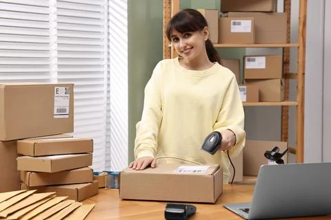 Parcel packing. Post office worker with scanner reading barcode indoors Photos