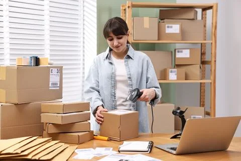 Parcel packing. Post office worker with scanner reading barcode at wooden t.. Photos