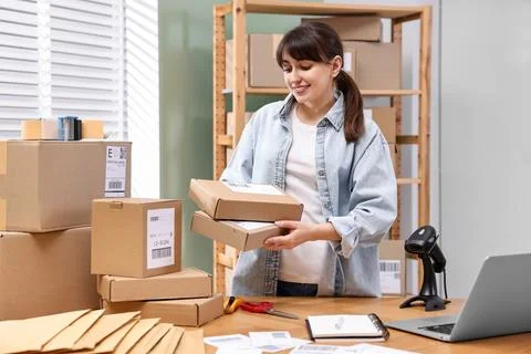 Parcel packing. Post office worker with parcels at wooden table indoors Stock Photos