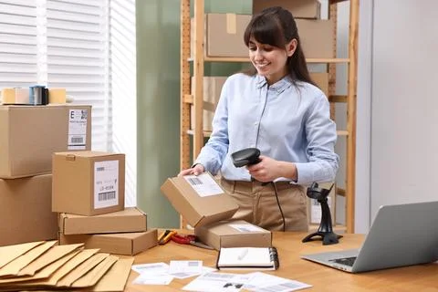 Parcel packing. Post office worker with scanner reading barcode at wooden t.. Foto stock