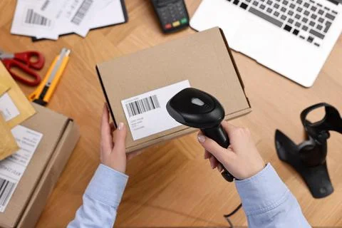 Parcel packing. Post office worker with scanner reading barcode at wooden t.. Photos