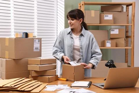 Parcel packing. Post office worker sticking barcode on box at wooden table .. Stock Photos