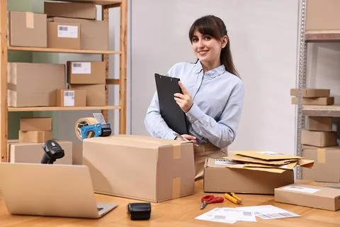Parcel packing. Post office worker with clipboard at wooden table indoors Foto stock