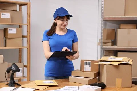 Parcel packing. Post office worker with clipboard at wooden table indoors Stock Photos
