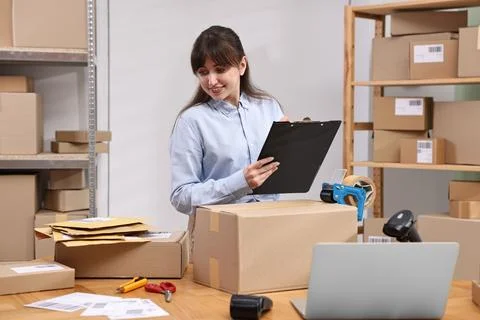 Parcel packing. Post office worker with clipboard writing notes at wooden t.. Stockfoto's